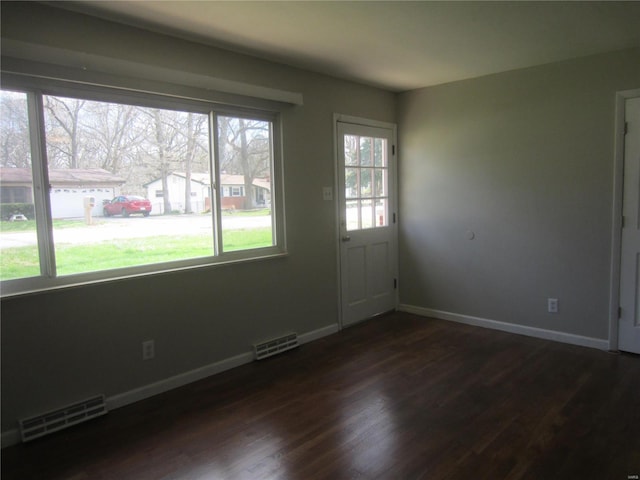 interior space featuring dark wood-style flooring, visible vents, and baseboards