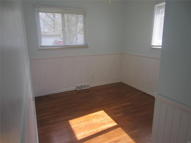 unfurnished room with wainscoting, wood finished floors, and visible vents