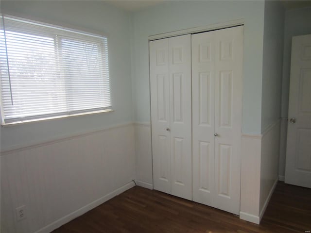 unfurnished bedroom with dark wood-style floors, baseboards, and a closet