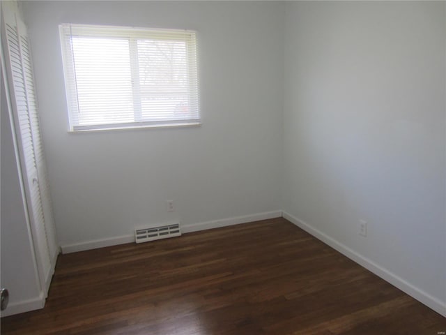 unfurnished room featuring dark wood-style floors, visible vents, and baseboards