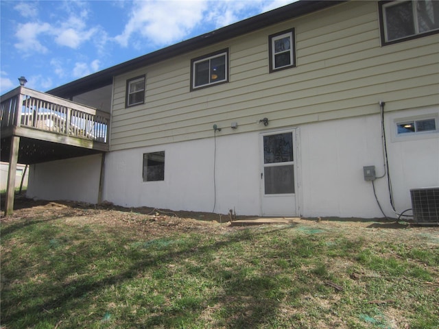 rear view of house with a lawn, a deck, and central AC