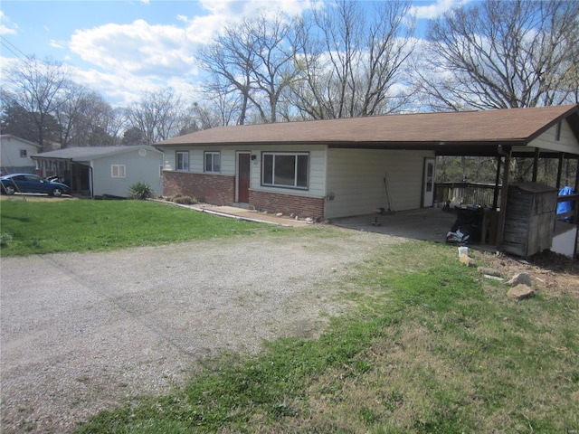 single story home with a front yard, brick siding, driveway, and an attached carport