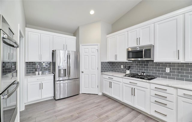 kitchen with light stone counters, light wood-style flooring, decorative backsplash, appliances with stainless steel finishes, and white cabinets