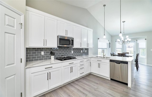 kitchen featuring stainless steel appliances, white cabinets, a sink, and a peninsula