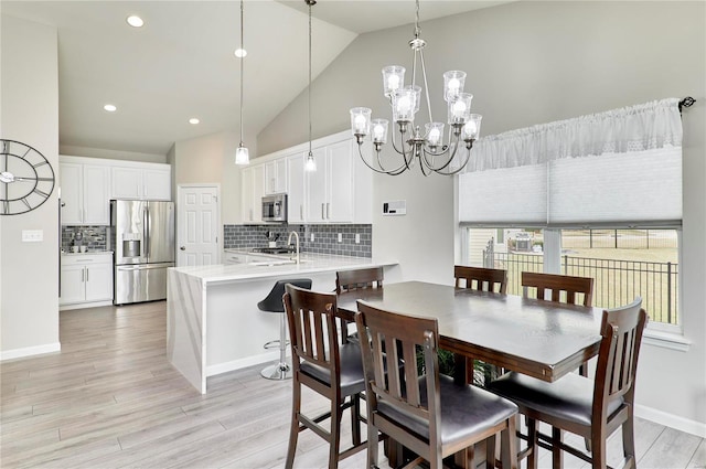 dining area featuring light wood finished floors, baseboards, high vaulted ceiling, a chandelier, and recessed lighting