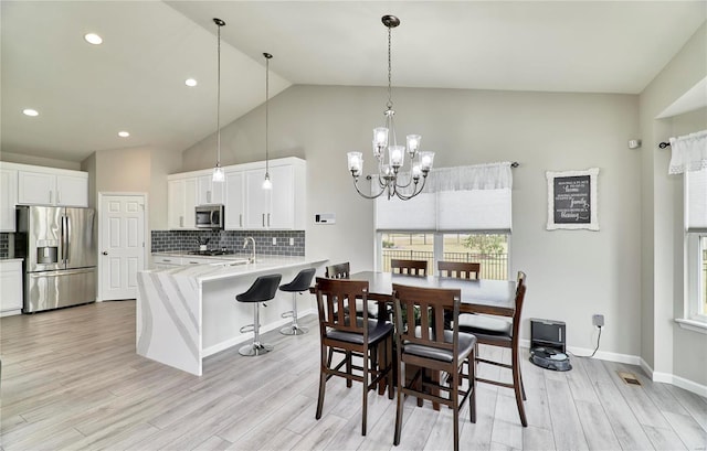 dining space with light wood finished floors, baseboards, visible vents, and a chandelier