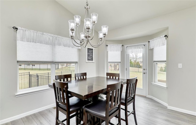 dining space featuring a chandelier, light wood finished floors, and baseboards