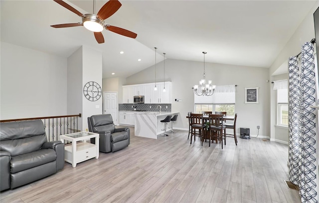 living area featuring high vaulted ceiling, light wood-type flooring, baseboards, and recessed lighting