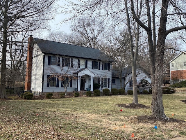 colonial home featuring a chimney and a front yard