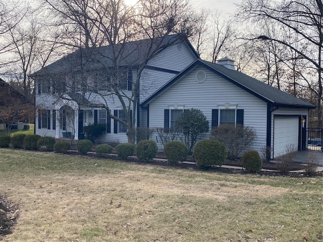 colonial-style house featuring a garage, a chimney, and a front lawn