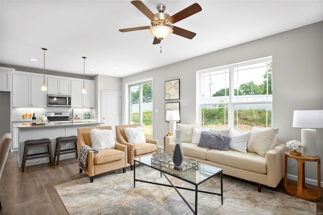 living area featuring ceiling fan, recessed lighting, baseboards, and light wood-style floors