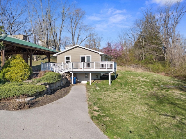 view of front facade with a deck, driveway, and a front yard