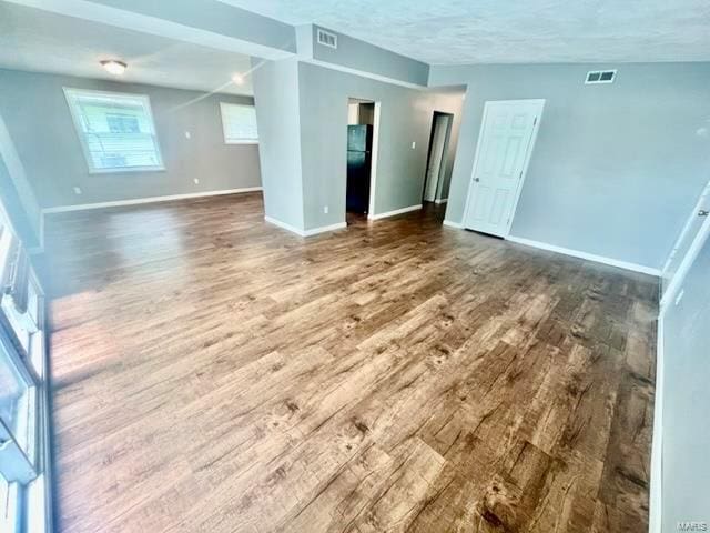 spare room featuring visible vents, baseboards, and wood finished floors