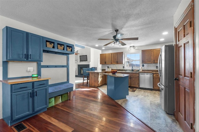 kitchen featuring visible vents, appliances with stainless steel finishes, a center island, a fireplace, and backsplash