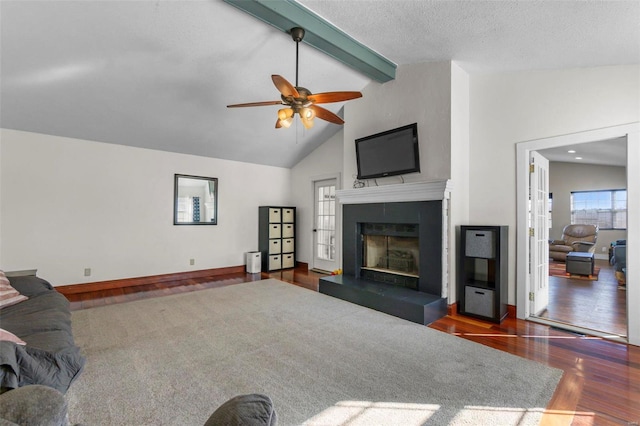 living area featuring beam ceiling, baseboards, a tiled fireplace, and wood finished floors