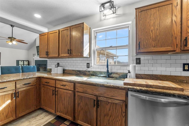 kitchen with a sink, vaulted ceiling, backsplash, brown cabinets, and dishwasher