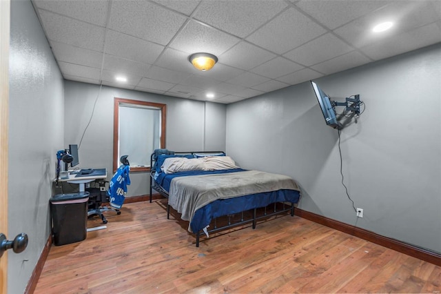 bedroom featuring recessed lighting, a drop ceiling, wood finished floors, and baseboards