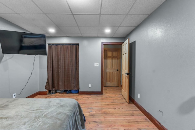 bedroom with light wood finished floors, a drop ceiling, recessed lighting, and baseboards