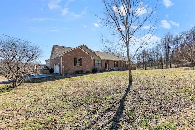 view of side of home with brick siding, a yard, and driveway