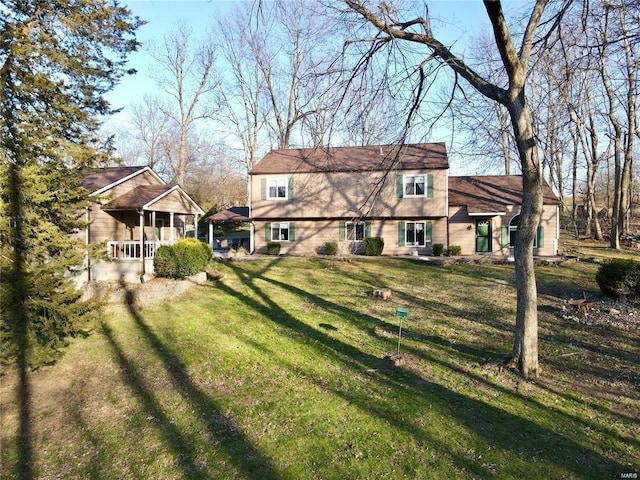 back of property with covered porch and a lawn