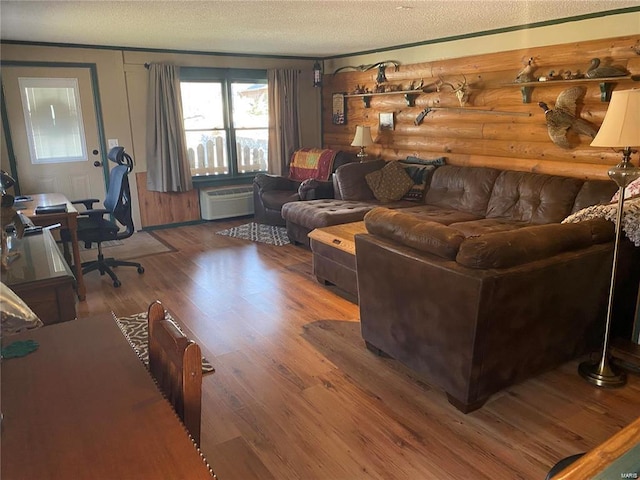 living room with log walls, a textured ceiling, and wood finished floors