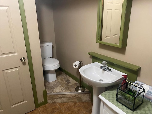 bathroom featuring baseboards, a sink, and toilet