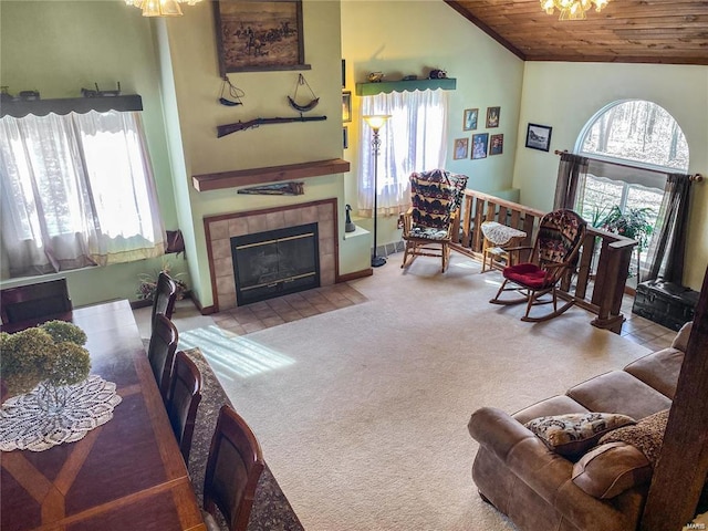 living area featuring high vaulted ceiling, wooden ceiling, light colored carpet, and a tiled fireplace