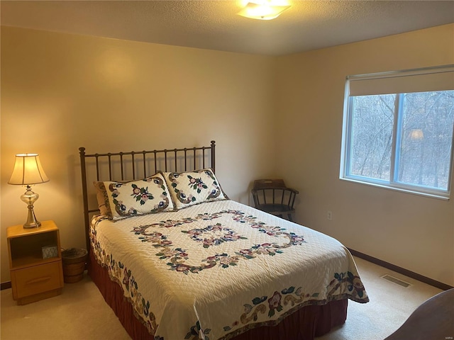 bedroom featuring light carpet, a textured ceiling, visible vents, and baseboards