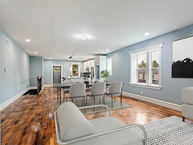 living room with recessed lighting, visible vents, baseboards, and wood finished floors