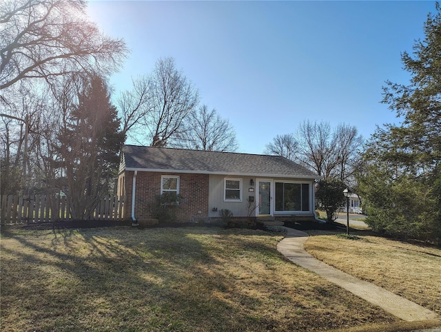 view of front of home featuring brick siding, a front lawn, and fence