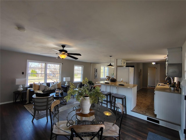 dining area featuring dark wood-style floors, baseboards, and ceiling fan