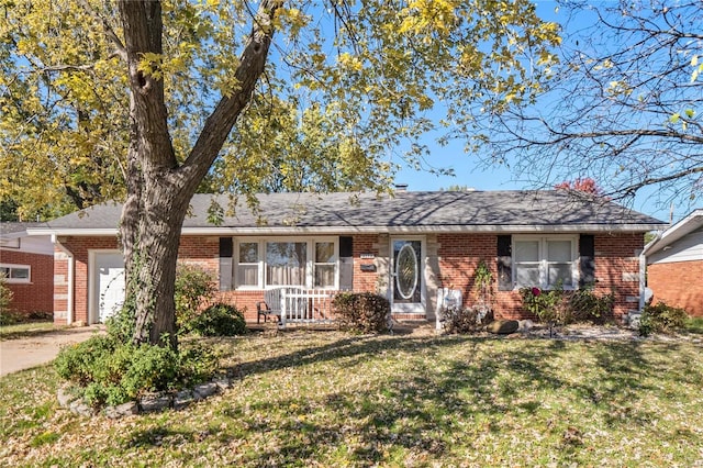 ranch-style house featuring brick siding, an attached garage, a shingled roof, and a front yard