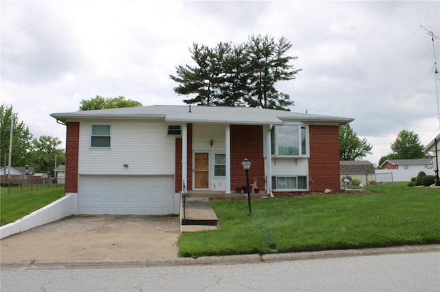 split foyer home featuring a garage, brick siding, fence, driveway, and a front lawn