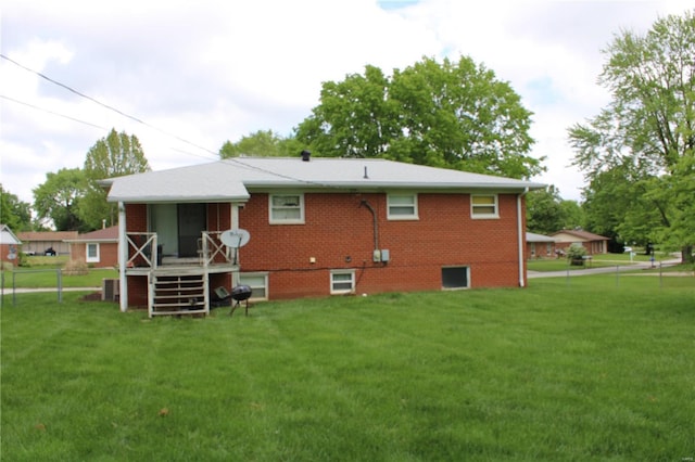 rear view of property with brick siding, a lawn, and stairway