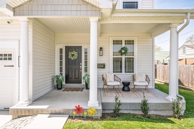 entrance to property featuring a porch and fence