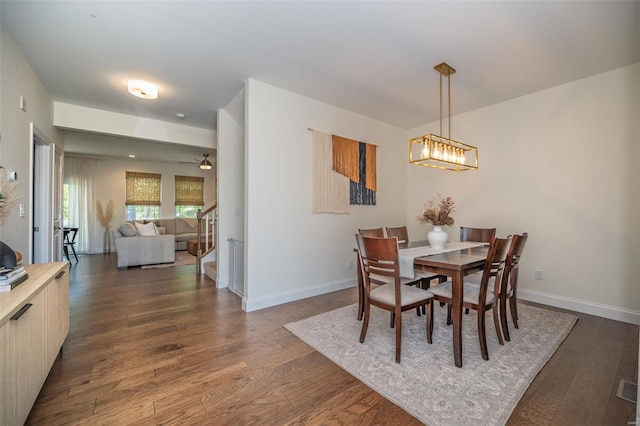 dining room with baseboards, ceiling fan with notable chandelier, and dark wood-type flooring