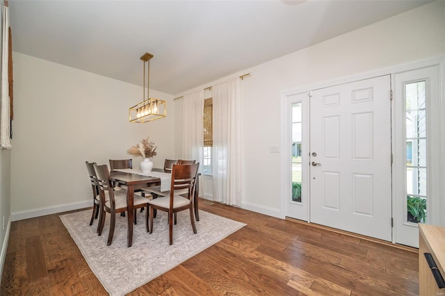 dining area with baseboards, a notable chandelier, wood finished floors, and a wealth of natural light