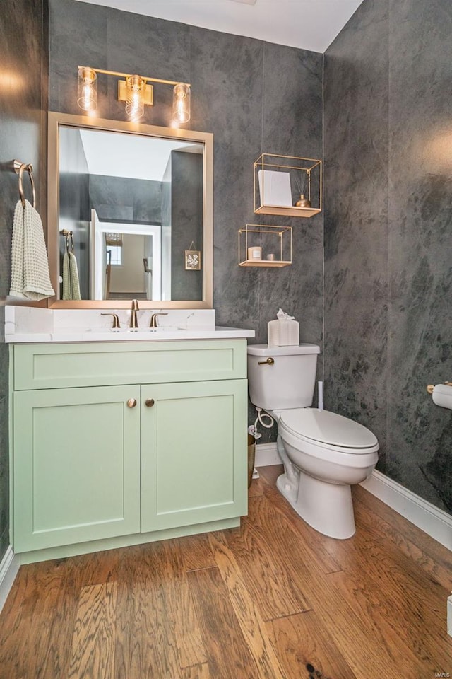 bathroom with vanity, baseboards, wood finished floors, and toilet