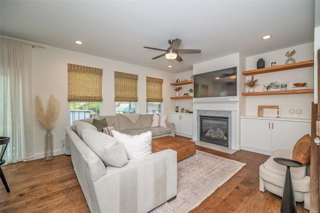 living room featuring a premium fireplace, ceiling fan, recessed lighting, and wood finished floors