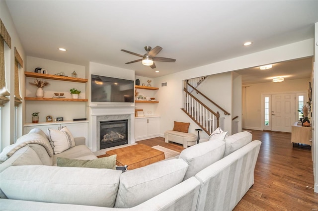 living room featuring ceiling fan, a premium fireplace, stairs, recessed lighting, and wood finished floors