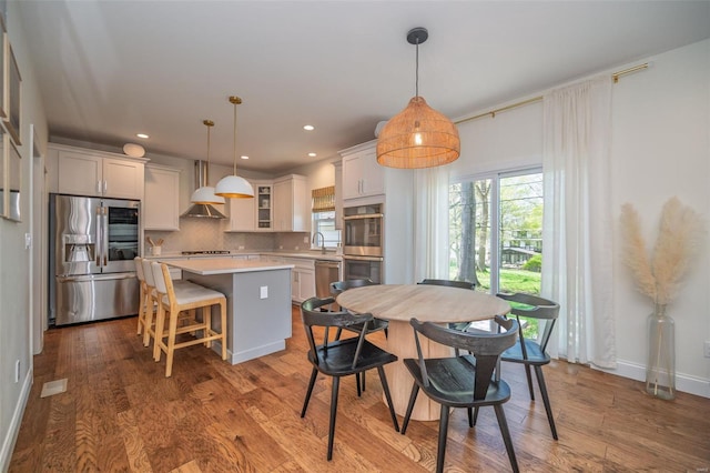 dining room featuring baseboards, wood finished floors, and a healthy amount of sunlight