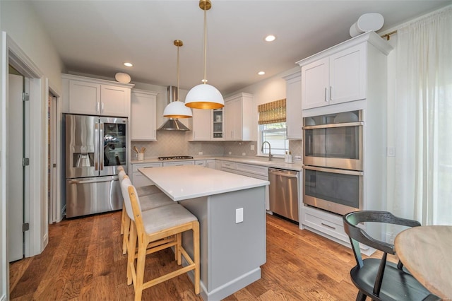 kitchen with a kitchen island, hanging light fixtures, tasteful backsplash, light countertops, and stainless steel appliances