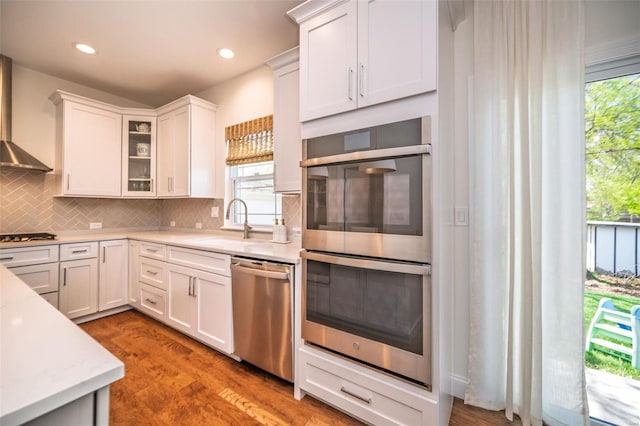 kitchen featuring glass insert cabinets, white cabinetry, a sink, appliances with stainless steel finishes, and backsplash
