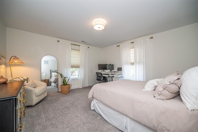 bedroom featuring carpet floors, arched walkways, and visible vents