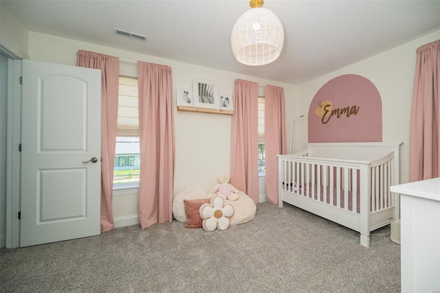 carpeted bedroom featuring visible vents, a crib, and multiple windows