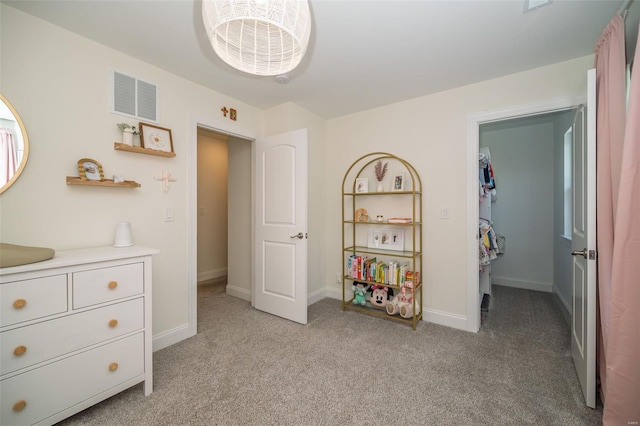 bedroom with visible vents, baseboards, a spacious closet, and light colored carpet