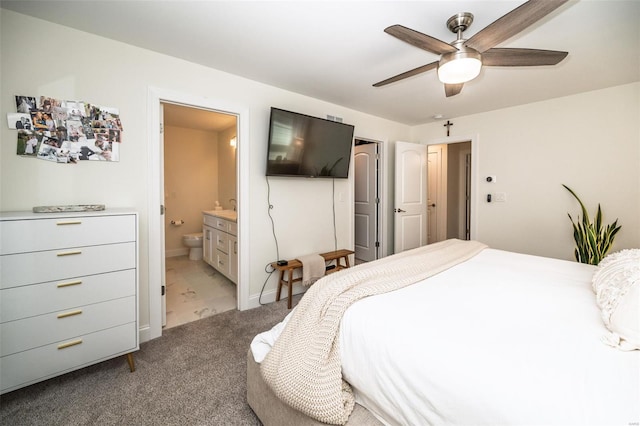 carpeted bedroom featuring baseboards, ensuite bathroom, and a ceiling fan