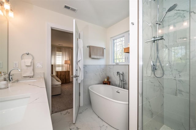 bathroom with visible vents, a freestanding tub, marble finish floor, tiled shower, and a sink