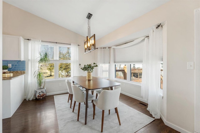 dining area with baseboards, visible vents, dark wood finished floors, an inviting chandelier, and vaulted ceiling