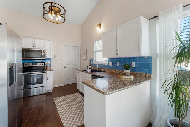 kitchen with a sink, backsplash, appliances with stainless steel finishes, white cabinets, and light stone countertops